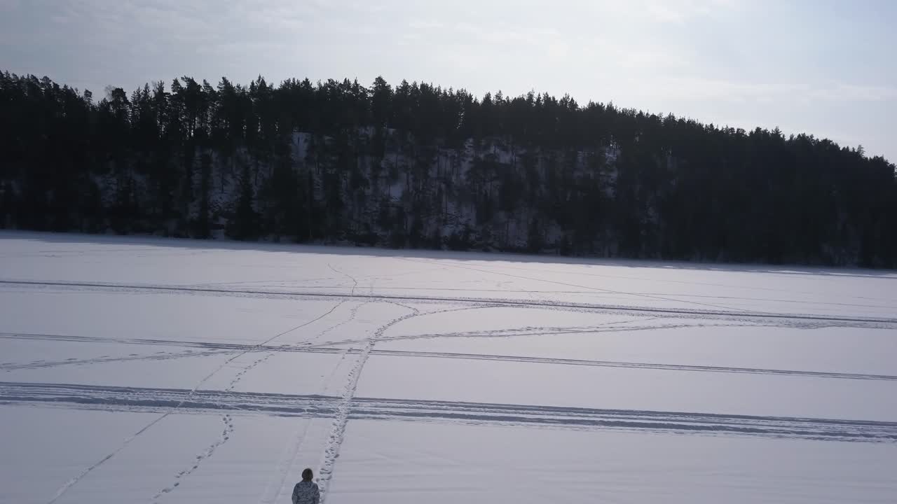 una joven rubia va a caminar por un desolado lago congelado para despejar su mente de la vida cotidiana
