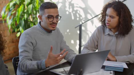 Businessman-With-Glasses-Sitting-In-Front-Of-The-Computer,-Talks-With-Two-Coworkers-About-A-Project-In-The-Office