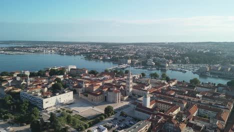 Zadar-on-a-summer-morning,-a-drone-footage-flying-backwards-and-revealing-Roman-forum-with-the-church-of-St