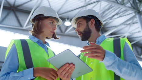 supervisors checking tablet discussing manufacturing information analysing