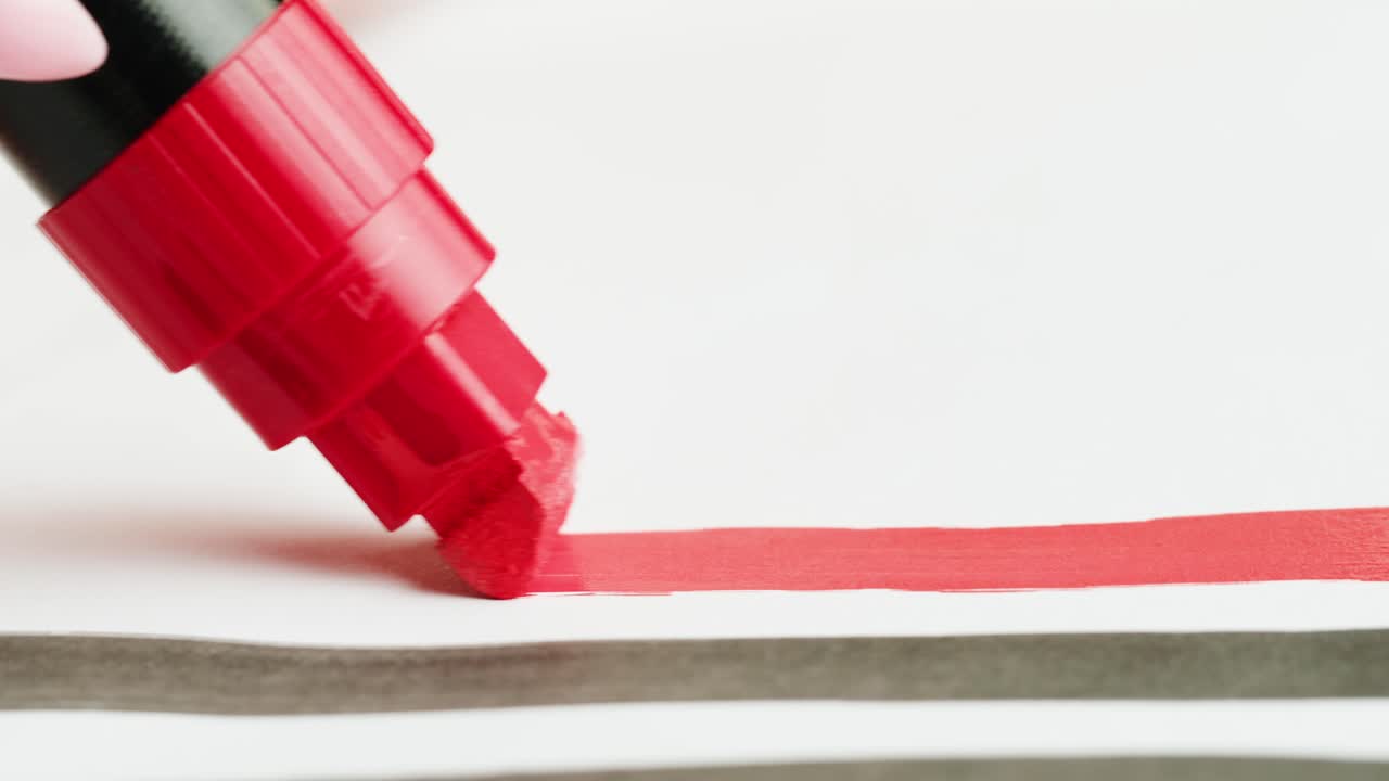 Hand Drawing a Red Line with a Marker on White Paper