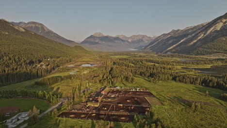 Banff-Ab-Canada-Drone-V24-Aéreo-Sobrevuelo-A-Los-Establos-De-Caballos-Que-Capturan-El-Paisaje-Rural-Con-El-Sinuoso-Río-Bow,-El-Valle-Boscoso-Y-Las-Cadenas-Montañosas-Al-Amanecer---Filmado-Con-Mavic-3-Pro-Cine---Julio-De-2023