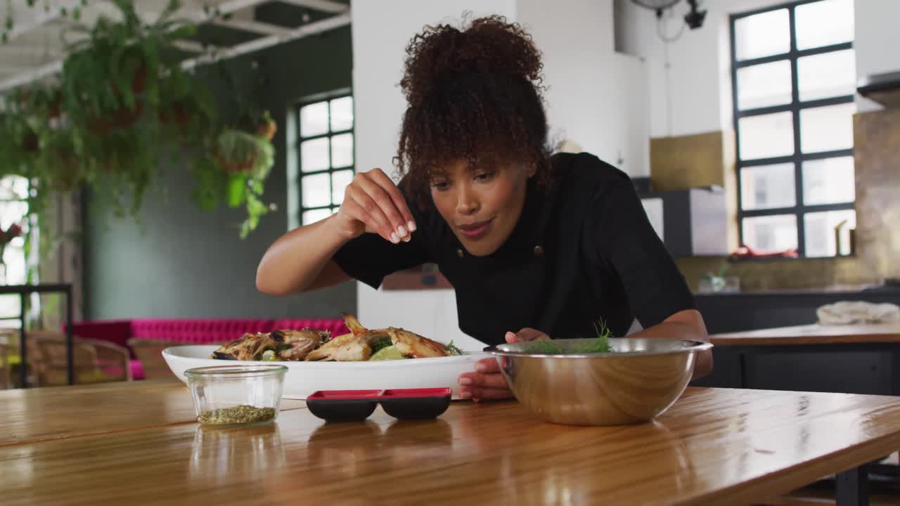 chef de raza mixta preparando un plato y sonriendo en una cocina