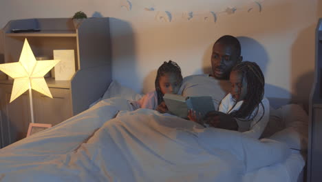 father reading bedtime story to girls