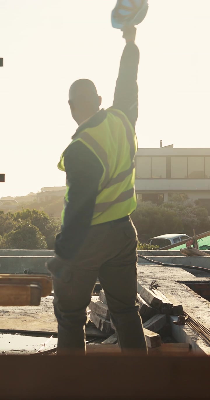 Construction Worker Celebrating Success on Building Site at Sunset