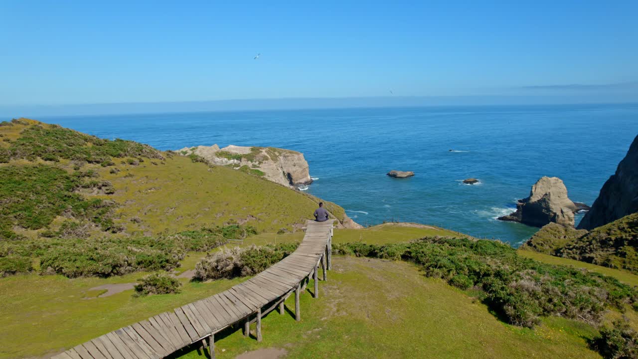 Aerial orbit establishing of a young man sitting on the Soul Pier, pier of souls meditating