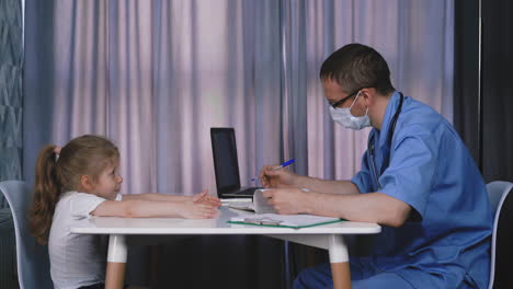 doctor in uniform and mask examines little girl in office