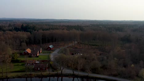 Drone-footage-of-a-car-driving-beside-a-lake-in-Sweden,-VÃ¤stersjÃ¶n-outside-Ã„ngelholm-in-SkÃ¥ne