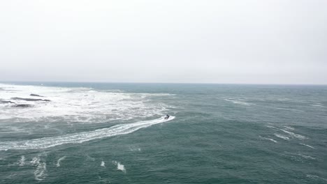 jet-ski-sailing-the-sea-surfing,-helping-and-rescuing-surfers,-perfect-waves-and-big-dangerous-waves,-drone-shot-following,-Pichilemu,-Punta-de-Lobos