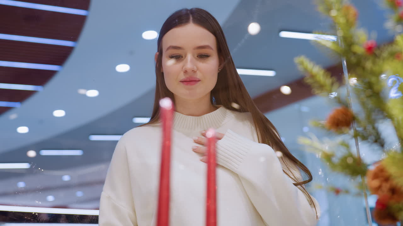 Elegant lady walking in beautifully decorated store, admiring holiday decorations and festive atmosphere inside stylish shopping mall with modern interior, glowing lights