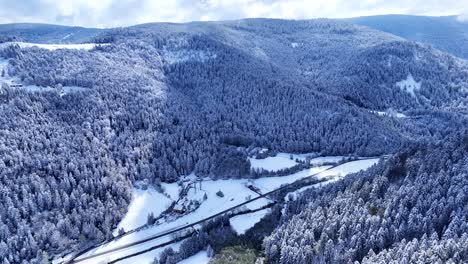 Drohne-Fliegt-Langsam-In-Einem-Im-Frühling-Mit-Schnee-Bedeckten-Gebirgstal-Mit-Blauem-Himmel-Und-Großen-Wolken