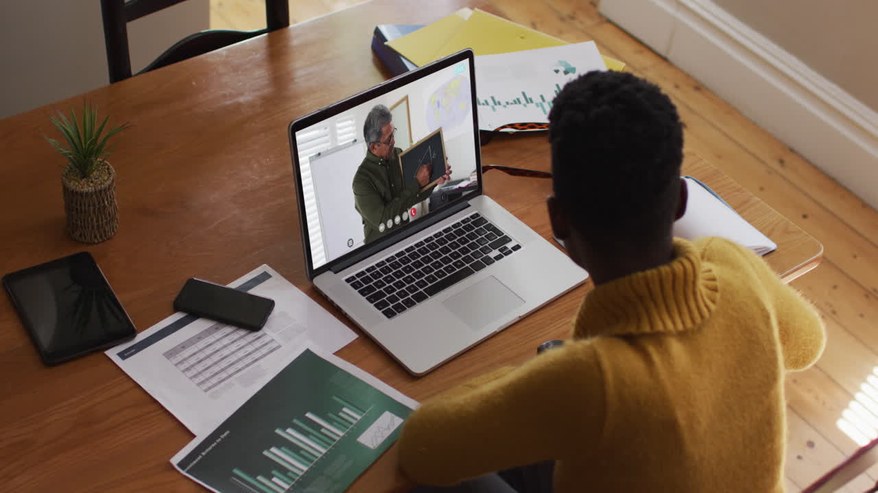 African american female student using laptop on video call with male teacher