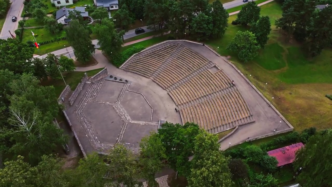 Cinematic aerial shot revealing amphitheater geometry in green Ikskile park