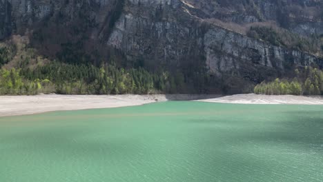 lago alpino con detrás una orilla de arena y montañas