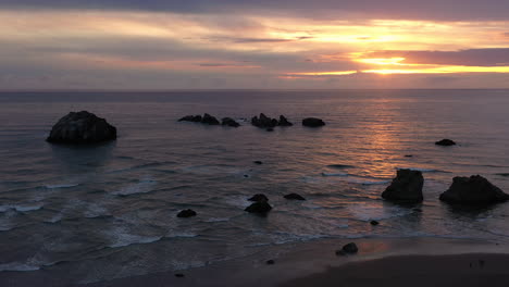 golden sunset sky over calm pacific ocean in bandon, oregon - face rock state scenic viewpoint - aerial shot