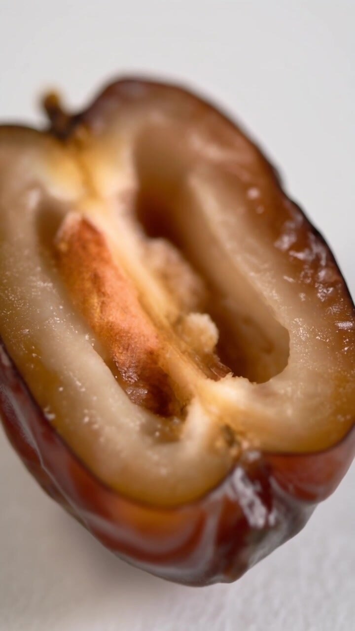 Extreme macro close up of a halved date showcasing its textured flesh and inner seed.