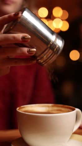 woman pouring sugar into cappuccino