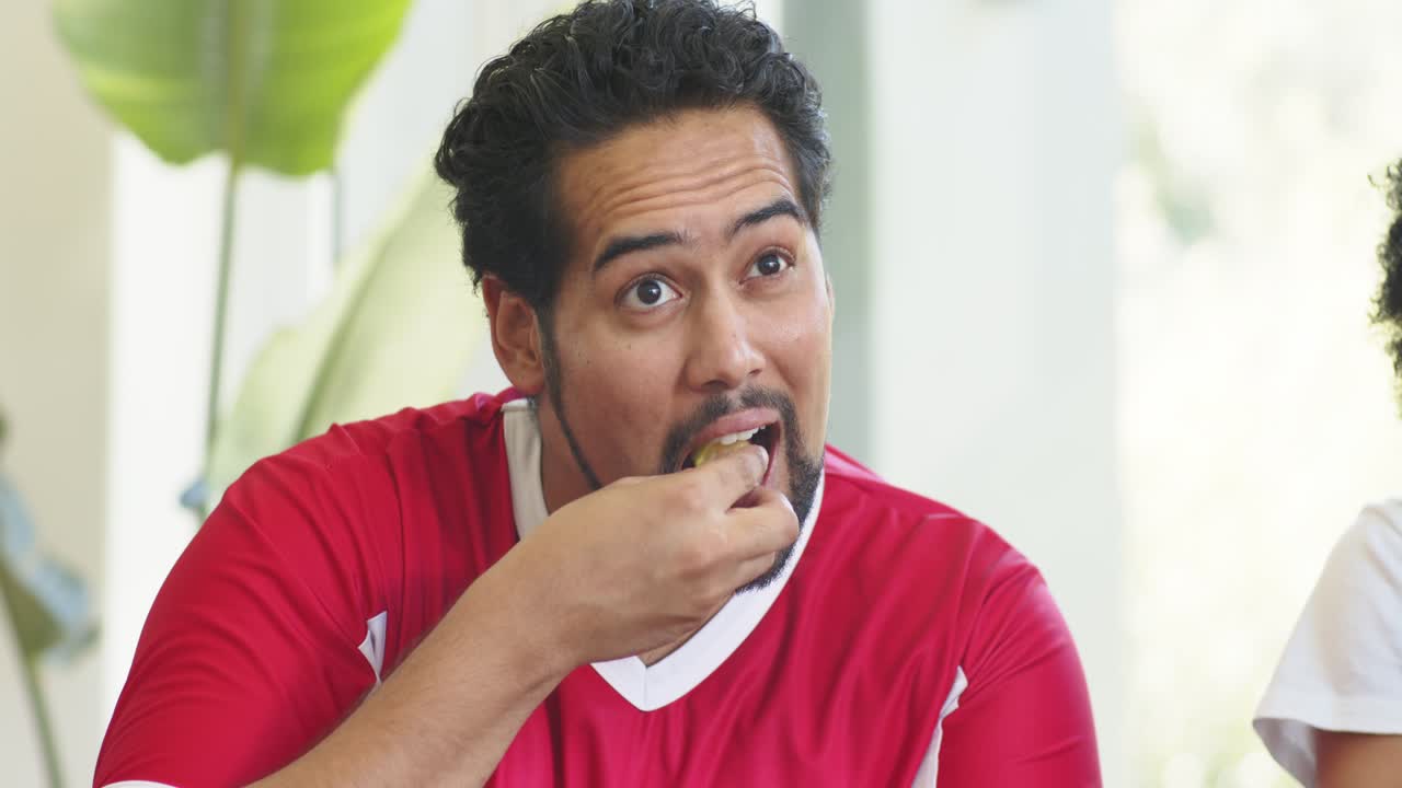 Amigos diversos começando o lanche, segurando um salgadinho, passando salgadinhos e bebendo de uma garrafa verde em casa