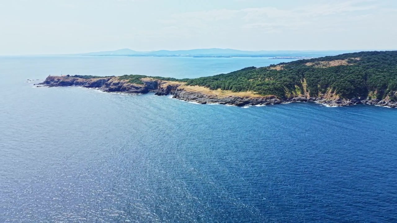 Veduta costiera di un'isola con oceano blu e colline verdi sullo sfondo durante il giorno