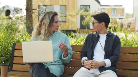 compañeras asiáticas y caucásicas discutiendo el trabajo en el parque