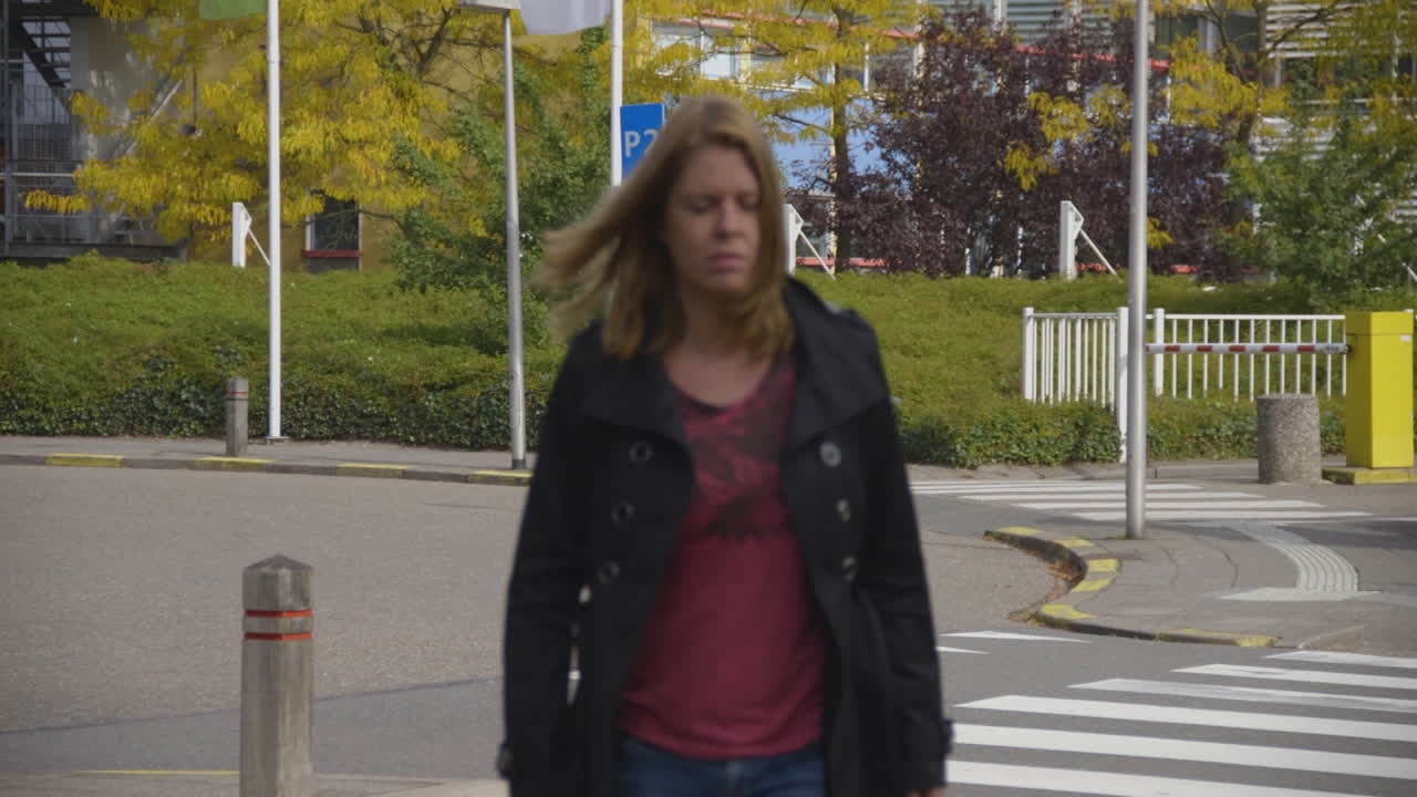 Una mujer aturdida camina por la carretera con un hospital de fondo.