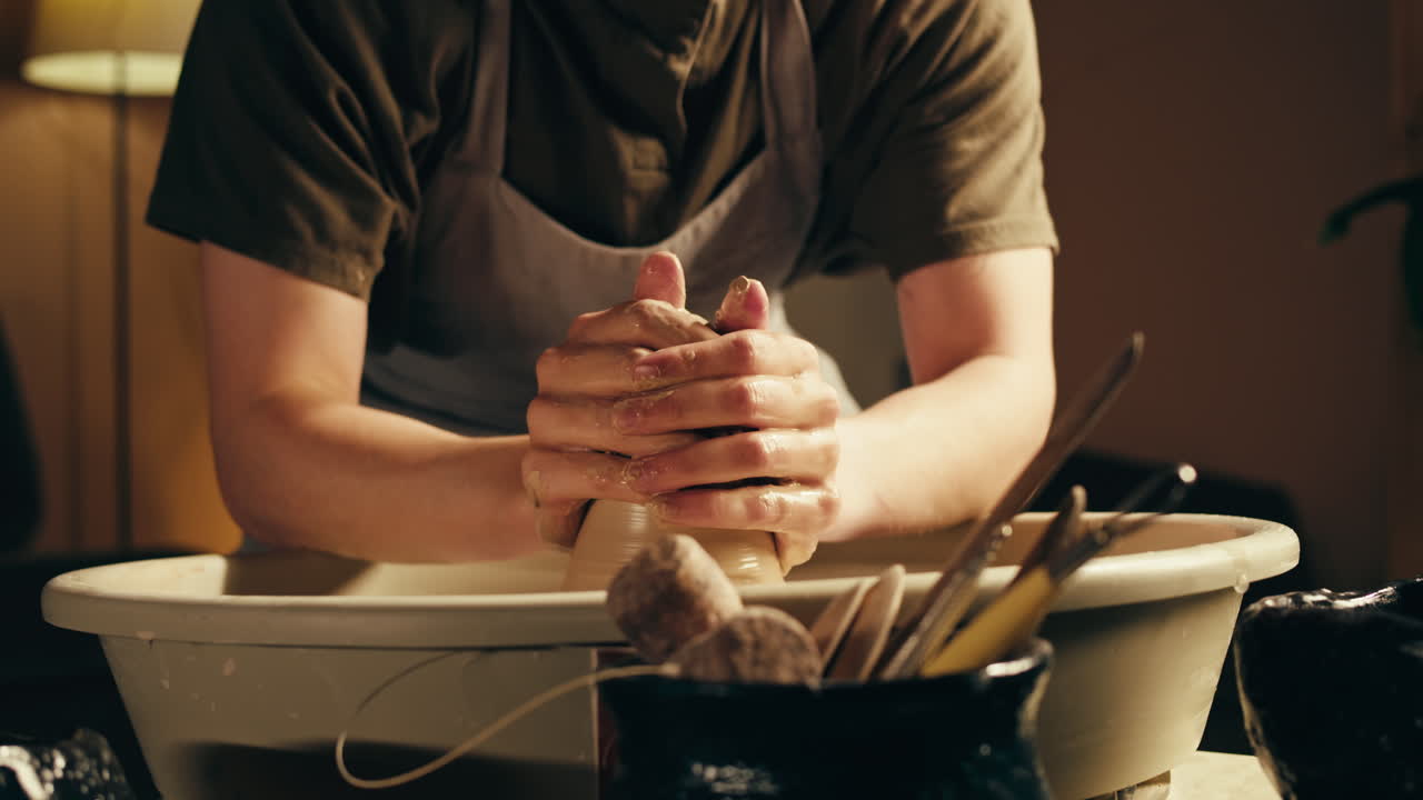 Person shaping clay on pottery wheel