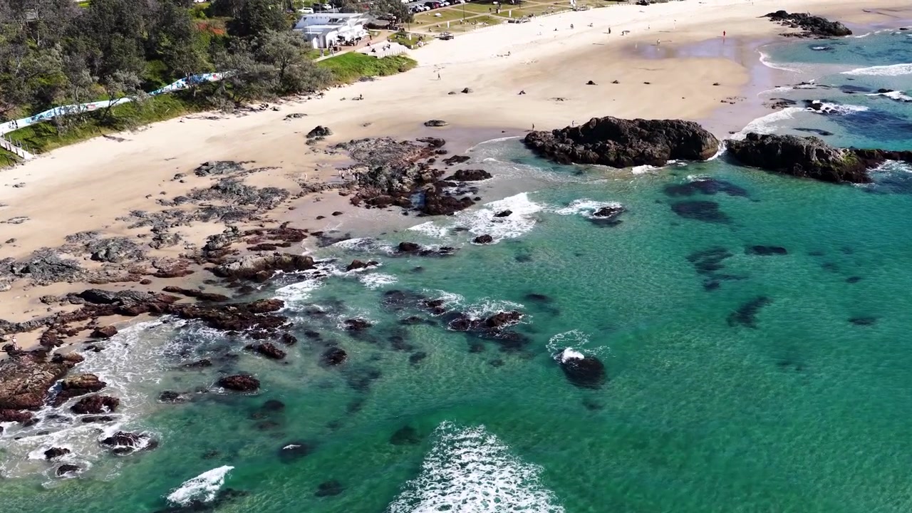 Vista aerea di onde oceaniche turchesi che si infrangono su una spiaggia rocciosa