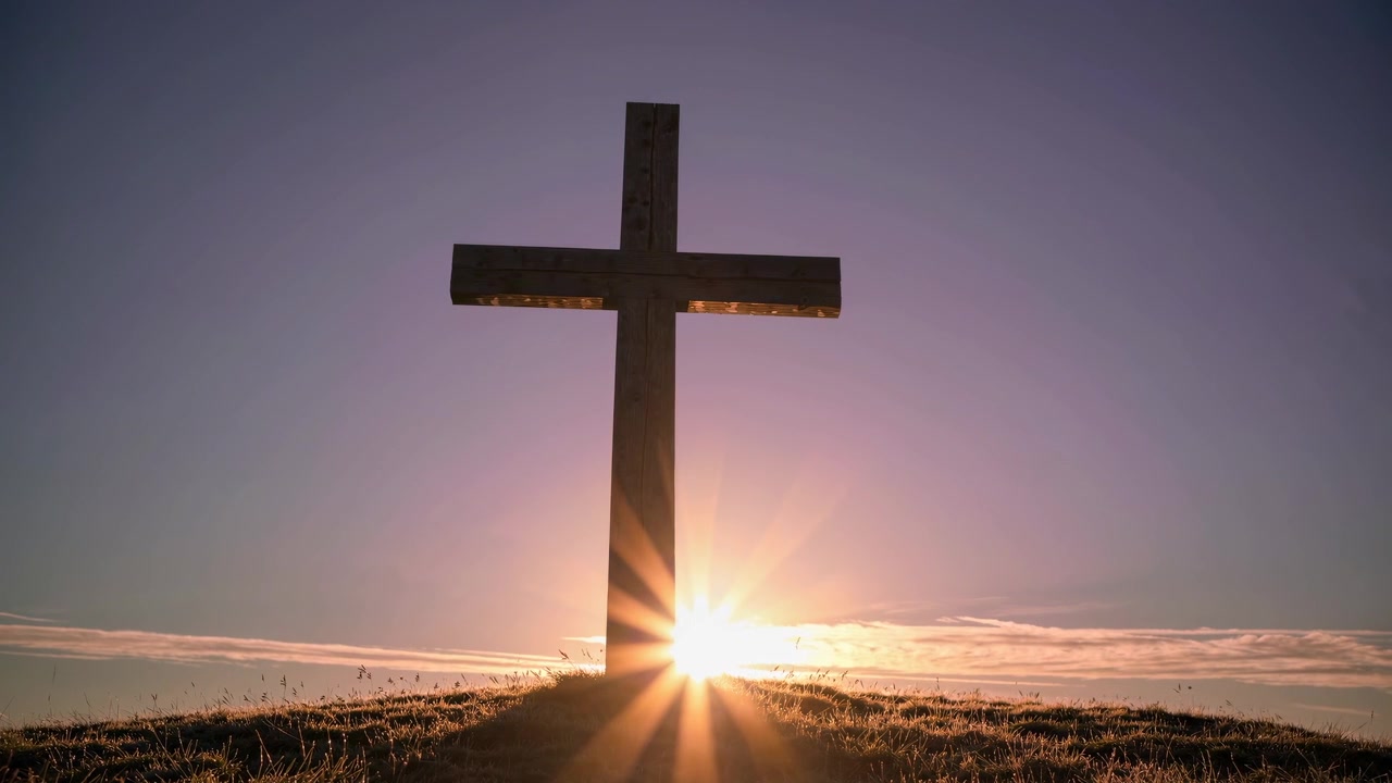 Alba dietro una silhouette di croce cristiana su una collina
