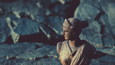 ancient statue of woman on rocky stones