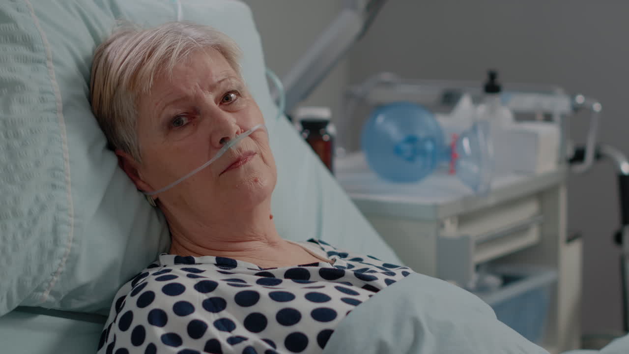 Portrait of elder woman with nasal oxygen tube laying in bed
