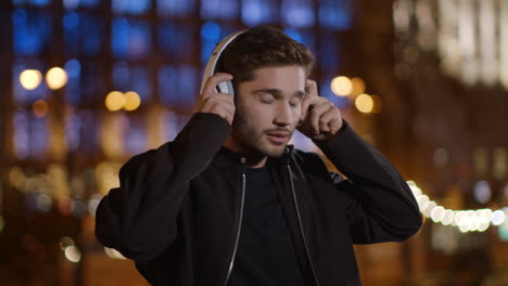 hombre guapo escuchando música a través de auriculares en la calle. tipo tranquilo relajándose al aire libre