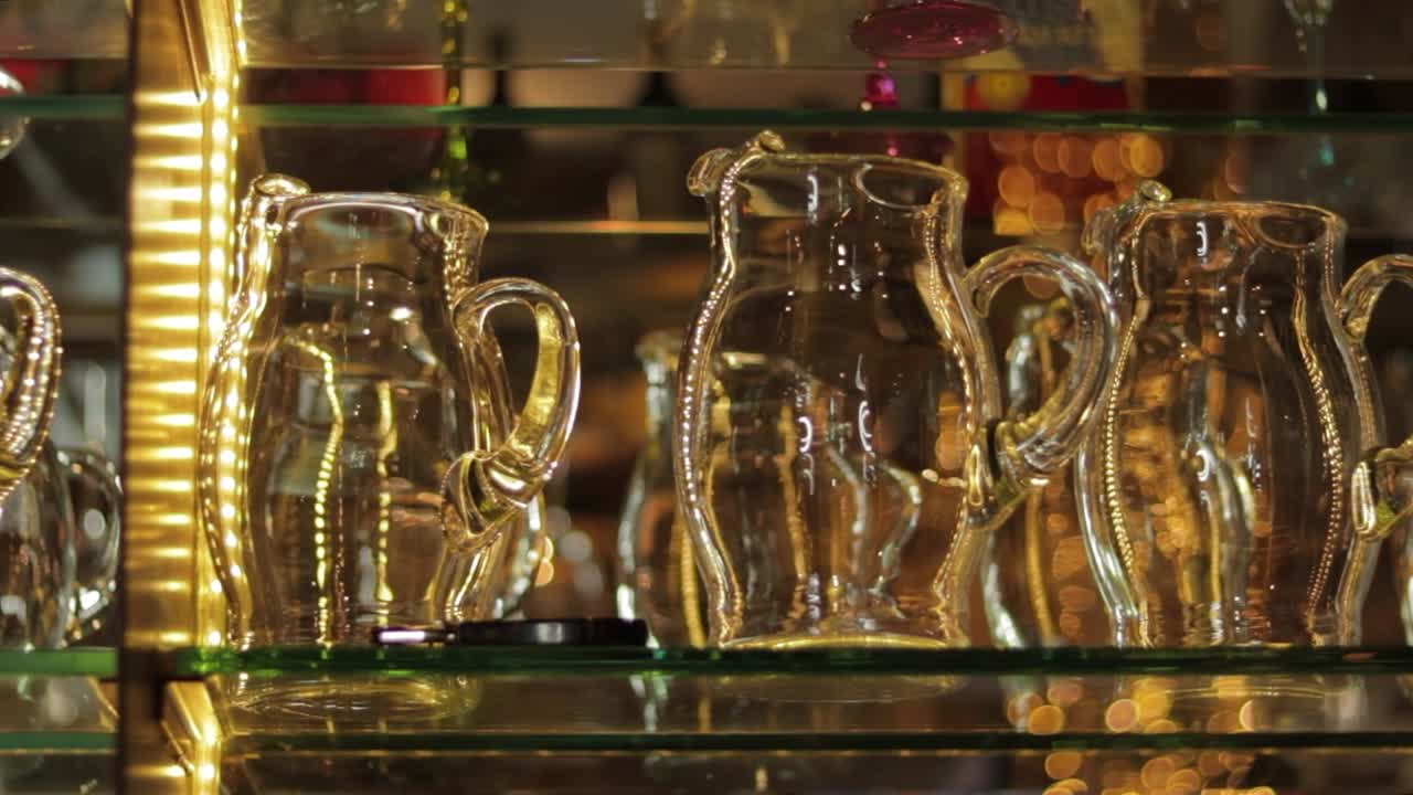 Empty glass jars arranged on glass rack shelves in restaurant bar
