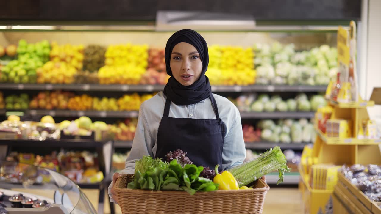 mujer musulmana en hijab camina con una canasta de verduras frescas en el supermercado, cámara lenta