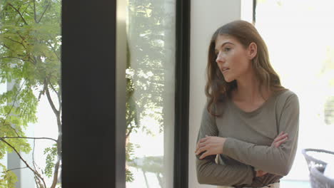 standing by window, woman looking outside with thoughtful expression, copy space