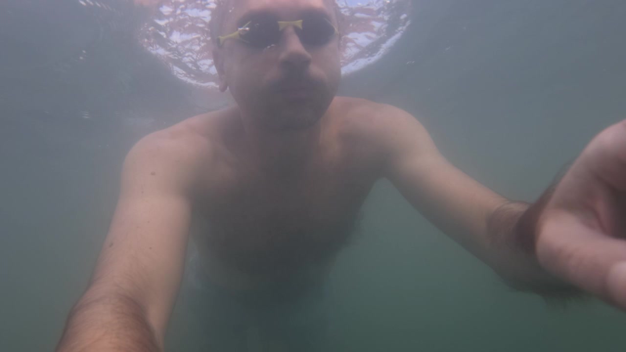 Undervandsoptagelse i slow motion af en svømmers arm, der bevæger sig gennem uklart vand, Côte d'Azur, Frankrig