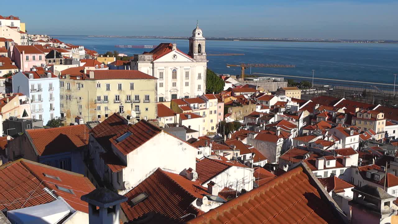 Vista panoramica sui tetti storici e i campanili delle chiese con il fiume Tago e le navi sullo sfondo in una giornata limpida e soleggiata