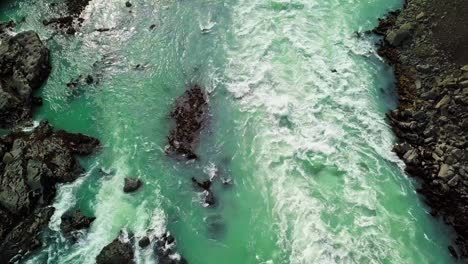 Fly-downstream-along-rushing-river-and-waterfall-with-turbulent-current-in-Iceland