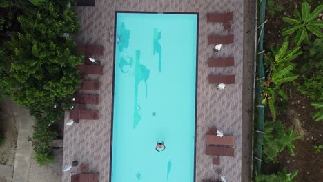 aerial view of a man swimming in a tropical resort pool