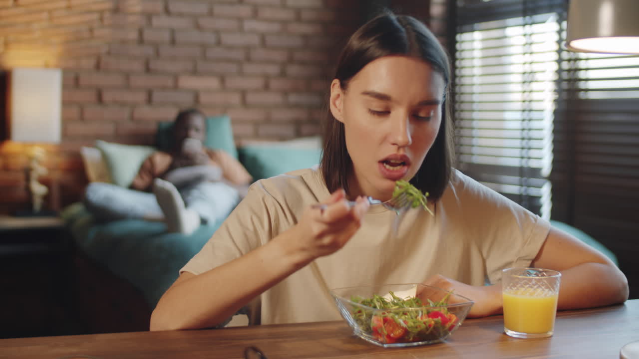 mujer joven comiendo ensalada y charlando en una llamada web