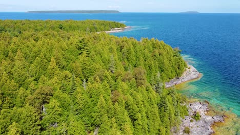 aerial drone shot following the beautiful coastline and crystal clear blue water of georgian bay, ontario, canada