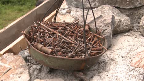 un recipiente lleno de clavos de construcción de metal oxidado usados