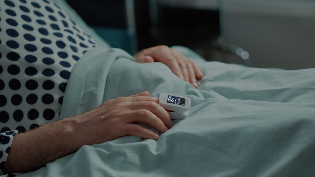 Close up of oximeter on patient in hospital ward bed