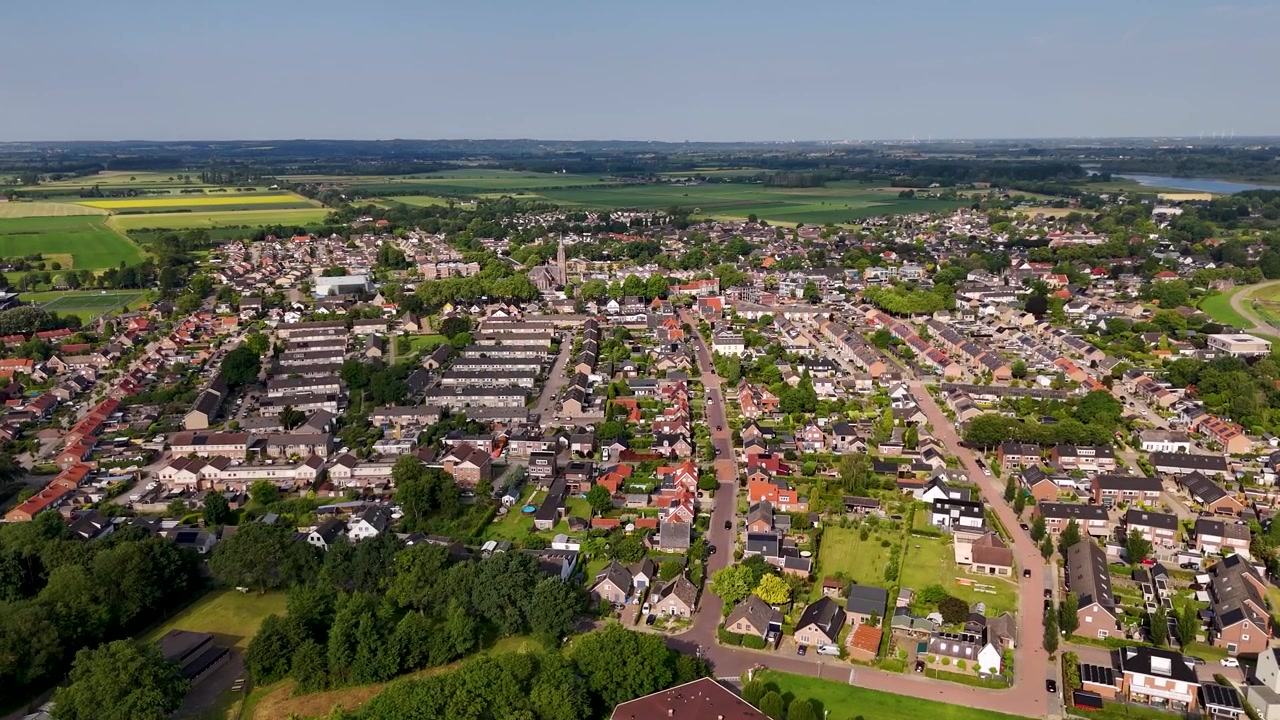 Luftaufnahme einer kleinen europäischen Stadt, umgeben von grünen Feldern.