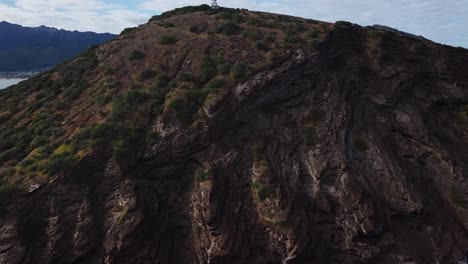 Drone-above-a-cliffside-beach-with-waves-crashing-and-houses-on-the-side-of-the-cliff