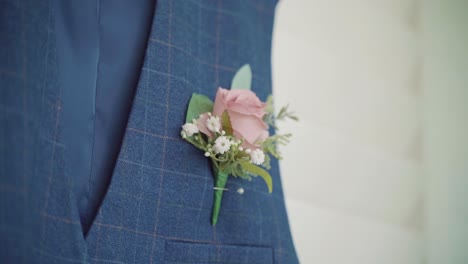 close up of a boutonniere on a grooms waistcoat