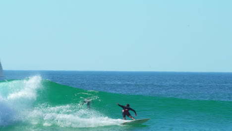 cinematic pan sigue a francia goofy rider surfeando justo al lado del velero derecho surfista masculino ola enorme se hincha por la mañana de día hossegor seignosse biarritz españa luz del día soleada wsl quiksilver roxy pro en traje de buceo