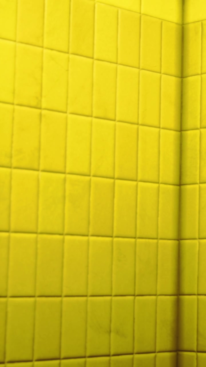 Bright yellow tiles create a unique atmosphere in a room near a corner