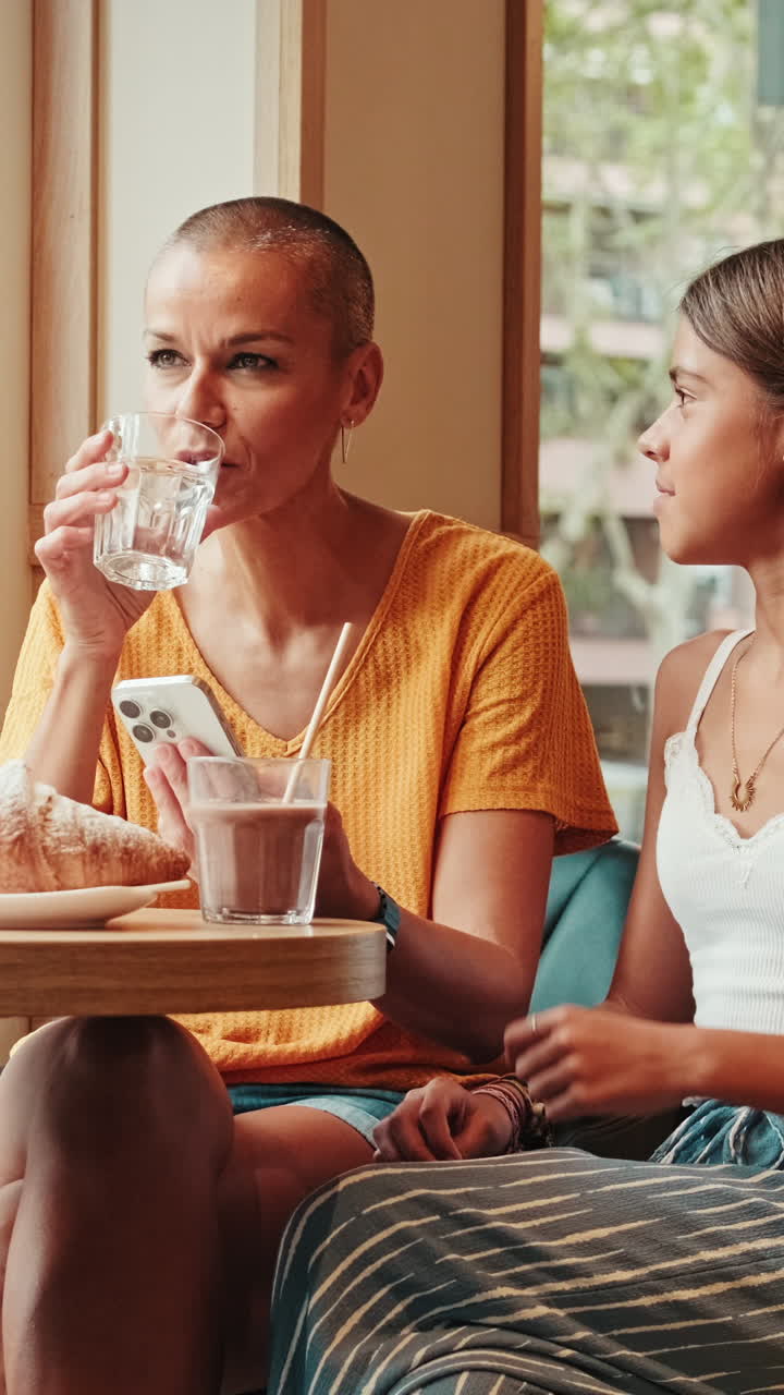 Mother And Daughter Share A Coffee And Phone