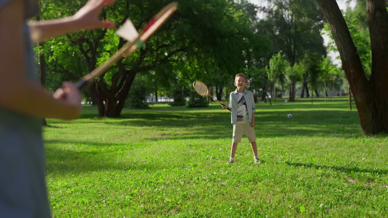 los niños alegres juegan al bádminton en el parque de verano.