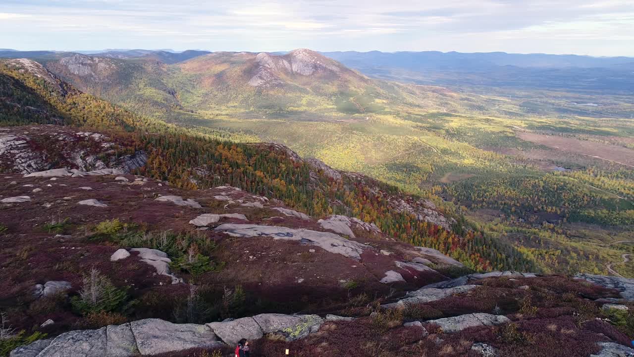 한 소녀가 나무 계단을 걷고 주변의 아름다운 산을 바라본다